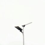 A minimalist solar-powered street lamp stands against a clear pale sky, emphasizing sustainability.